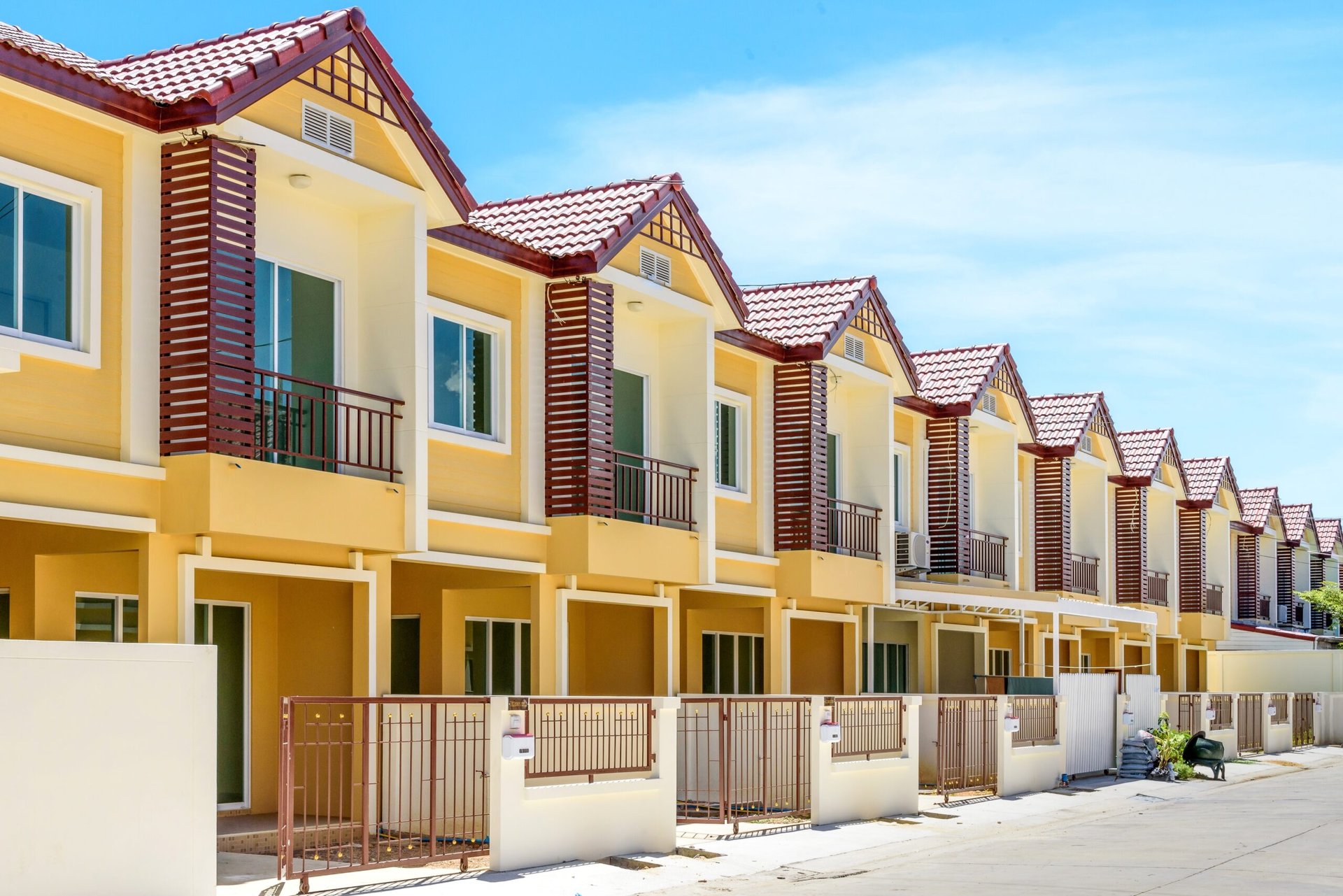 The row of just finished new yellow townhouses, Modern village buildings with blue sky, Concept of buying a house vs renting an apartment.