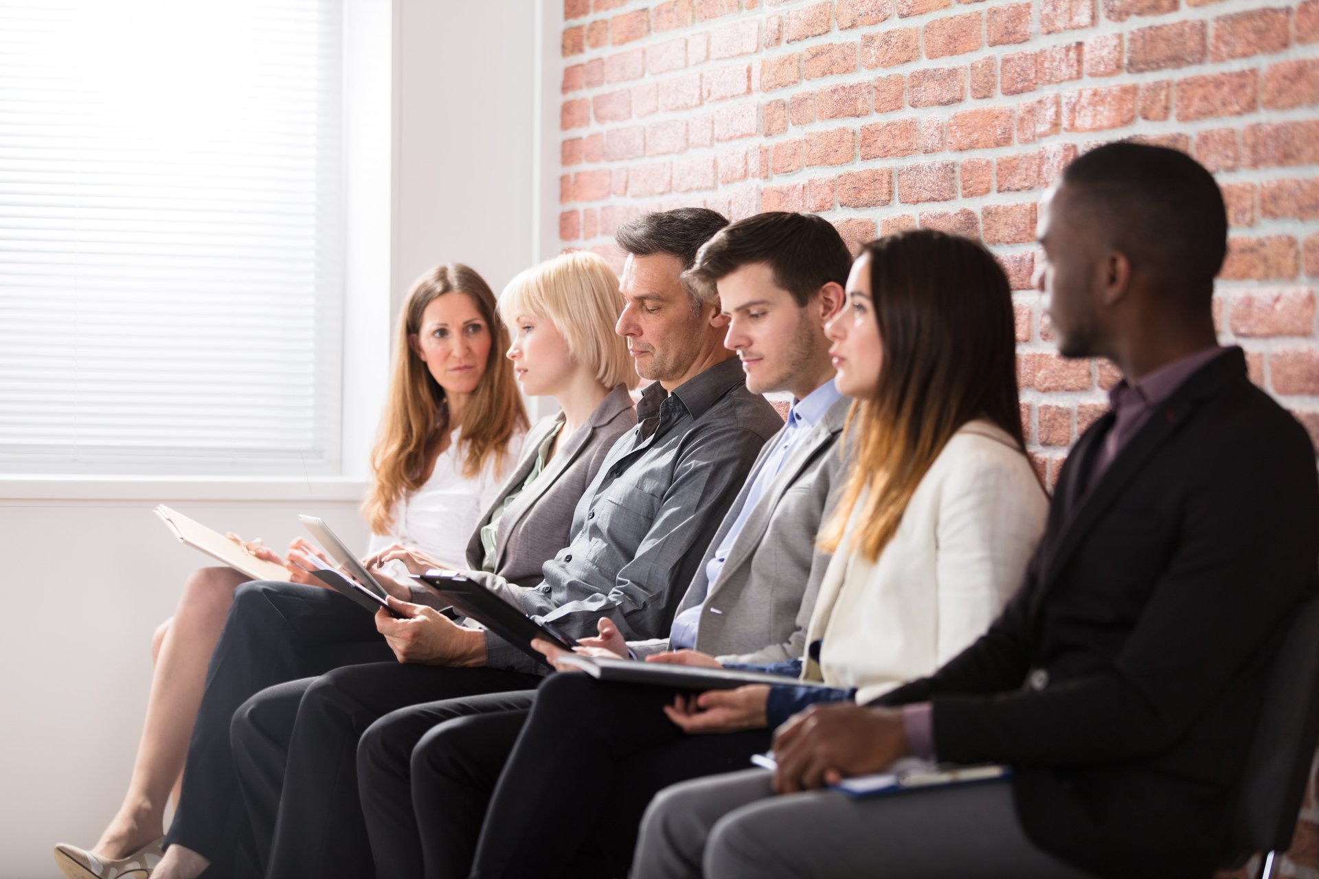 Prospective employees in business attire wait in line for job interviews