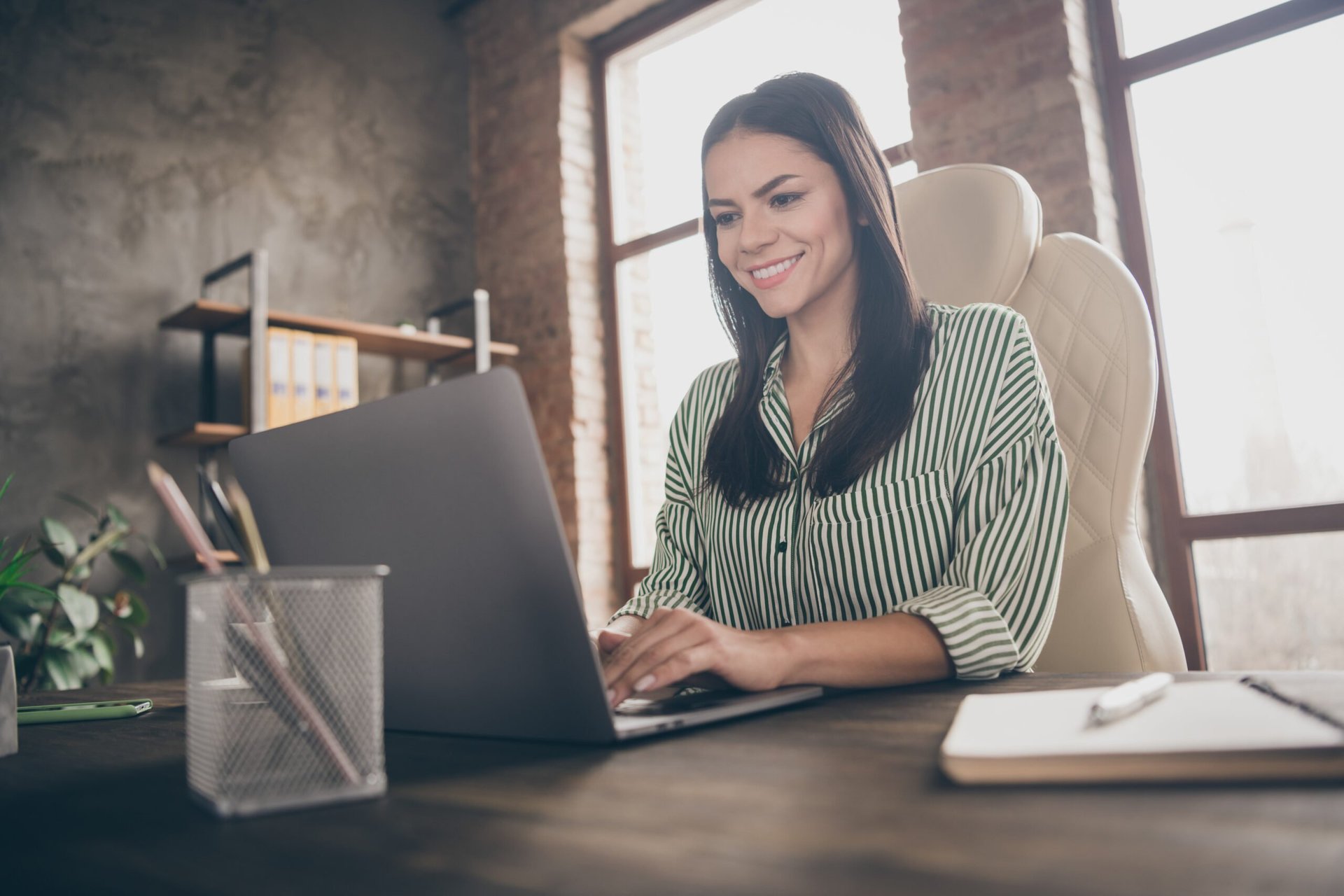 Woman working on a laptop from her home office.